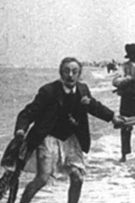 A 1905 Zandvoort newspaper recounts a French tourist napping on the beach who, as the tide rose, removed his trousers to protect them from saltwater. He fled a police officer, jumped into a passing car, hid in a changing cabin, but was captured and paraded with a marching band to the station. The spectacle was later admitted as a staged stunt by Messrs. Alberts Frères, merging the era’s local‑shot and chase film genres.